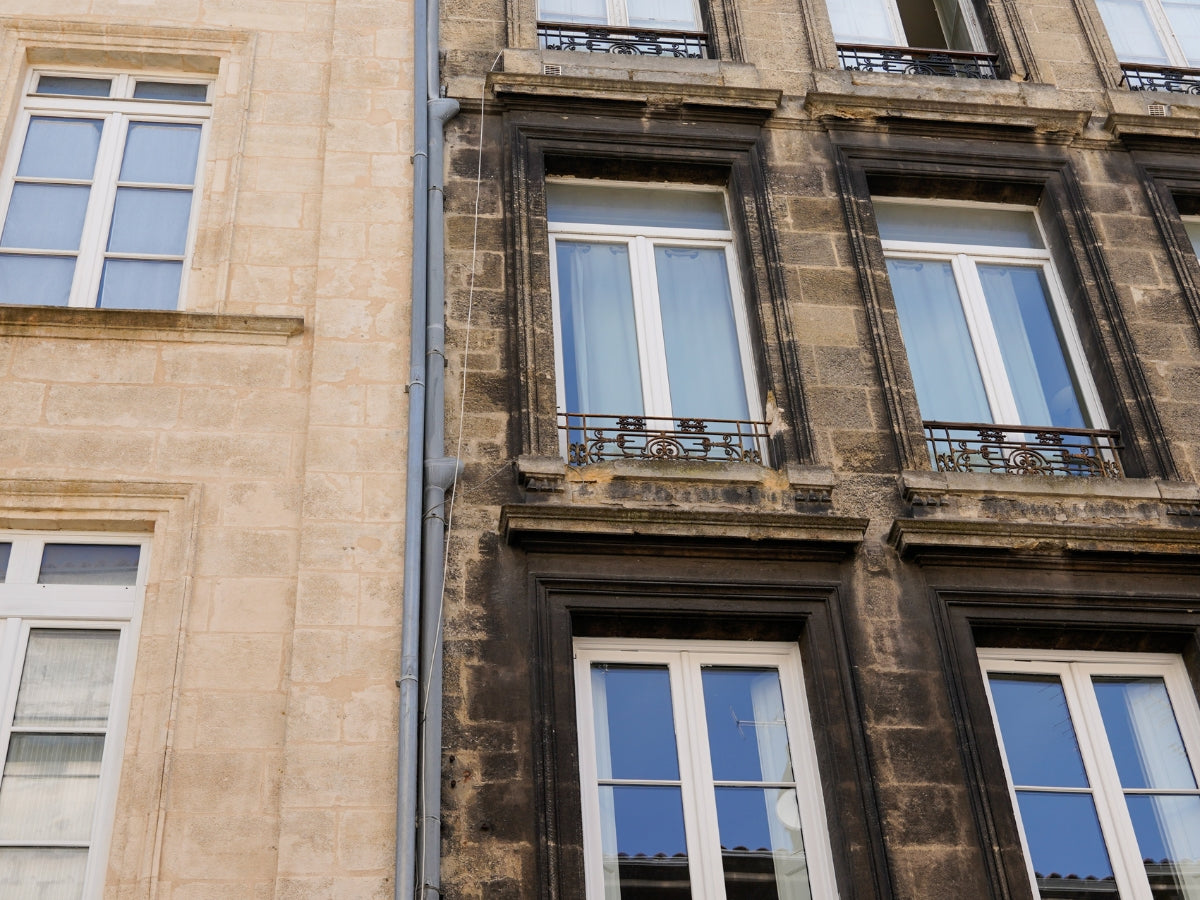 Commercial building facade being washed, with visible dirt removal and restored surface color, illustrating professional exterior washing services.
